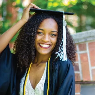 Photo of Faith Boyd smiling outdoors wearing cap and gown.